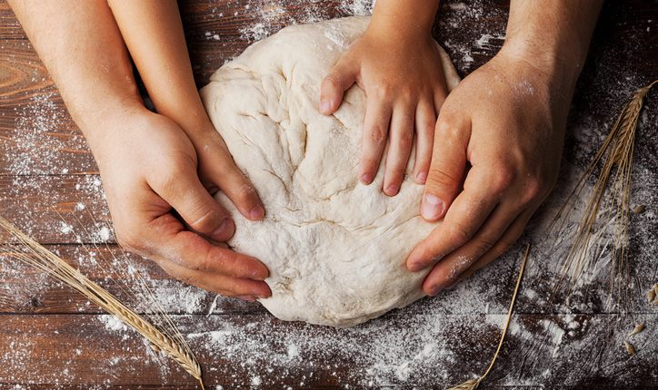 Father and child prepares dough with flour and wheat ears