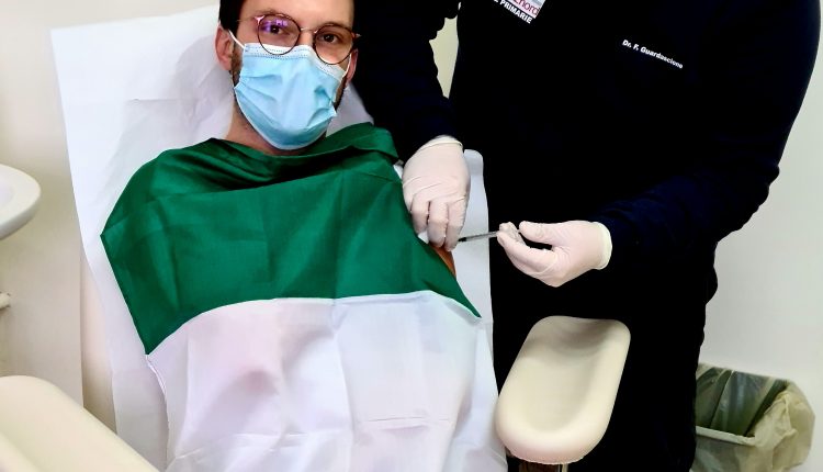 Raffaele Viola infermiere strumentista di sala operatoria si vaccina avvolto dal tricolore. “Onoriamo la nazione e il vaccino anti covid”